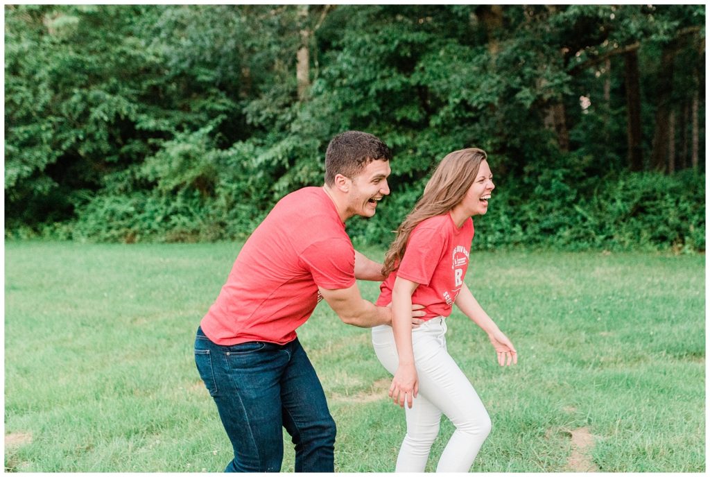 A couple wearing Rutgers T shirts runs through a field.