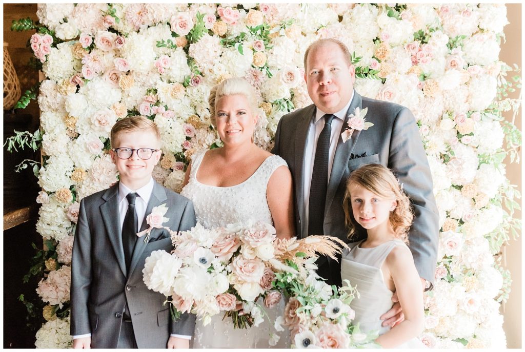 The bride and groom pose with their kids for a family photo.