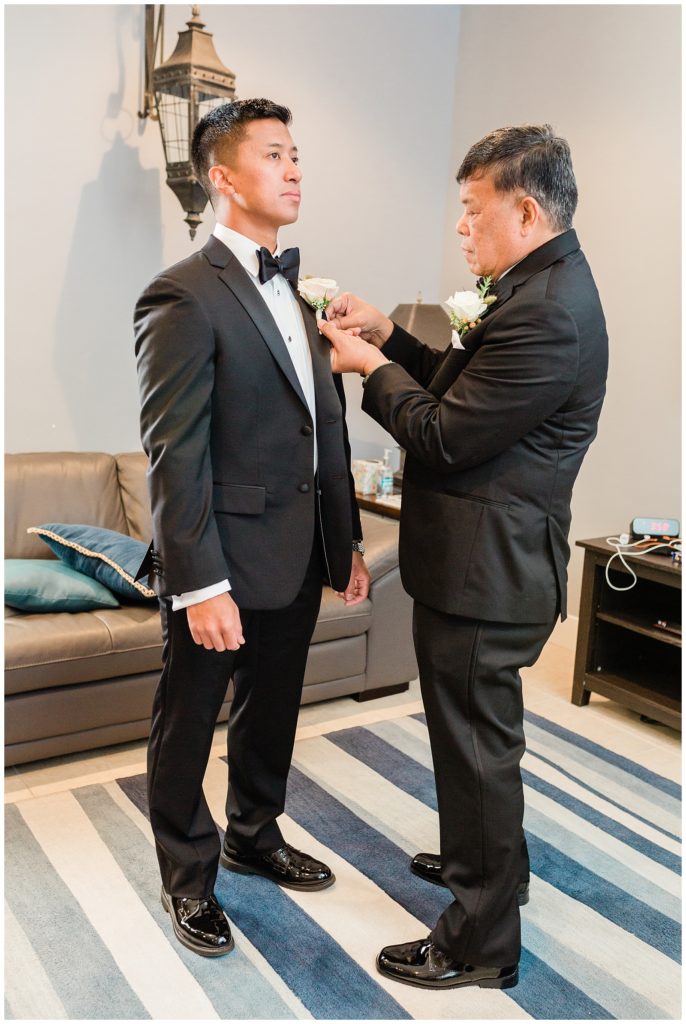 The groom's father pins his boutonniere on his wedding day in the groom suite at Avensole Winery in Temecula.