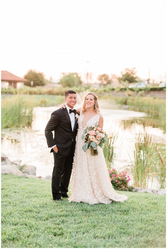 A bride and groom pose in front of a pond at Avensole Winery in Temecula, California.