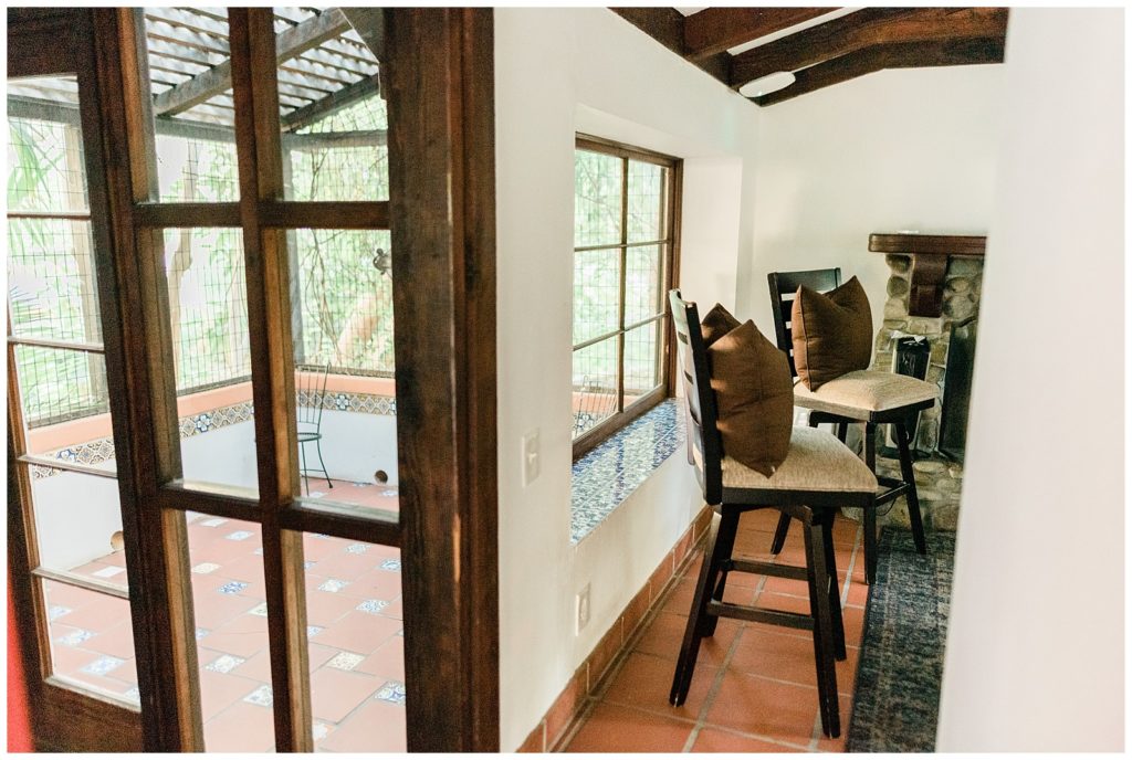 Interior view of the Rancho Las Lomas Groom's getting ready cottage showing barstool chairs and an enclosed porch.