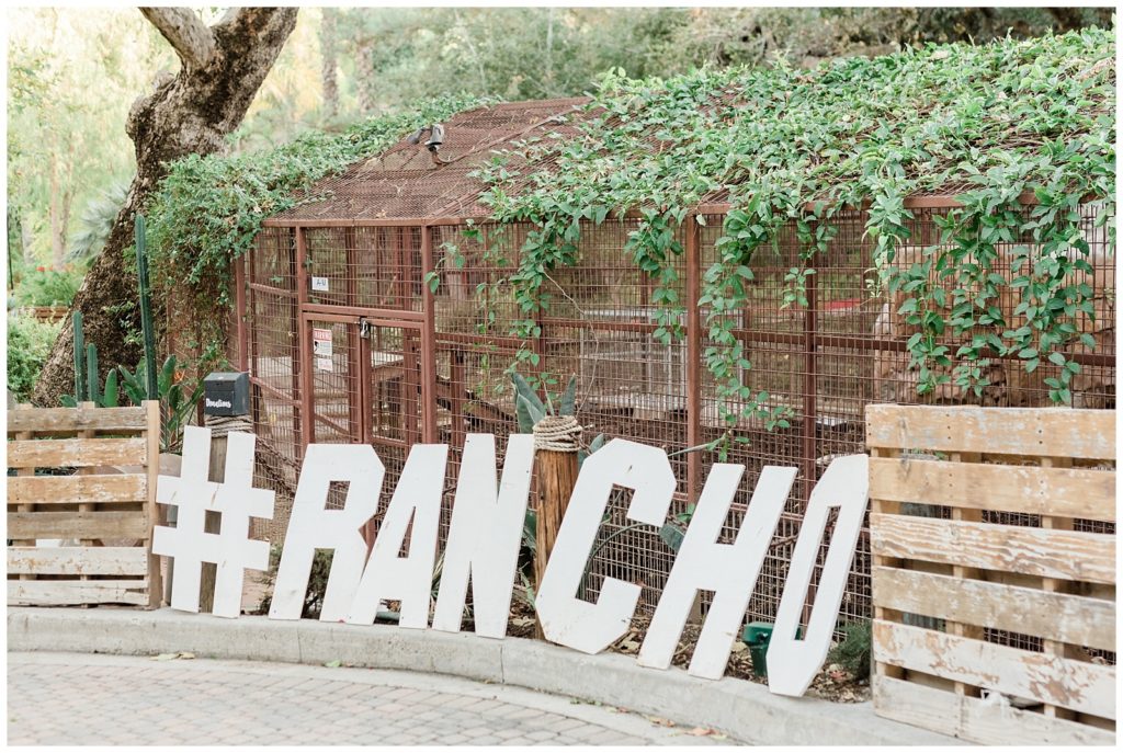 Giant cut out letters reading #RANCHO lay against a zoological animal exhibit at Rancho Las Lomas.