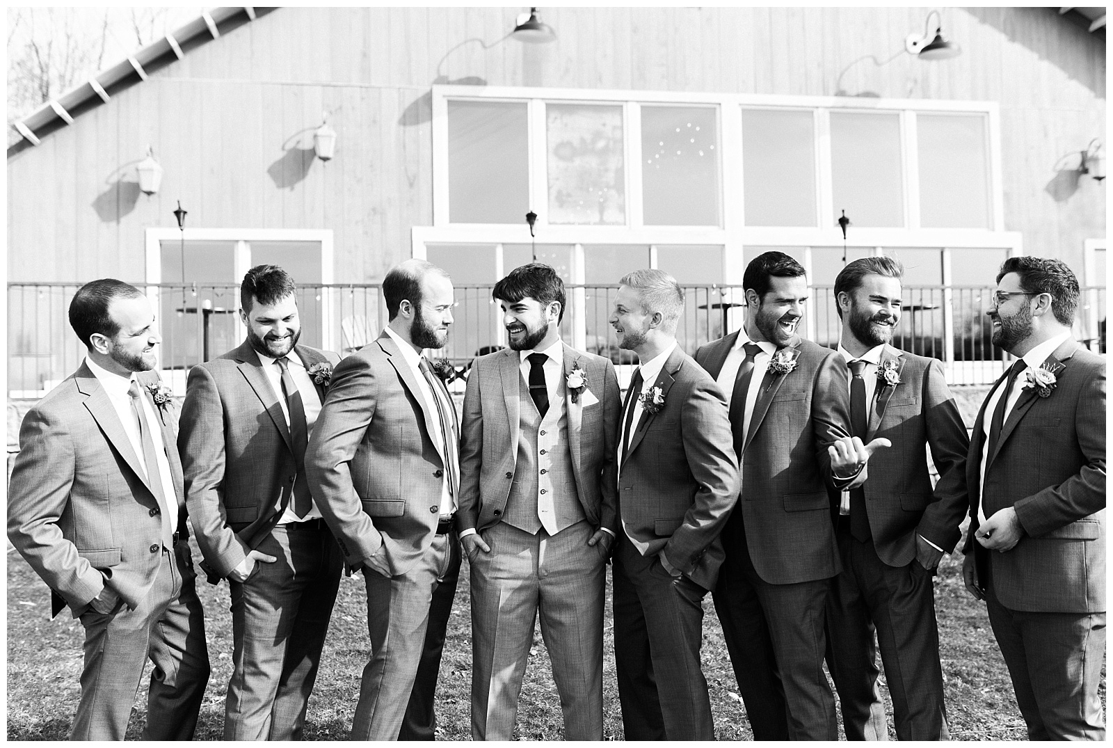 Groomsmen looking at each other and laughing in black and white.