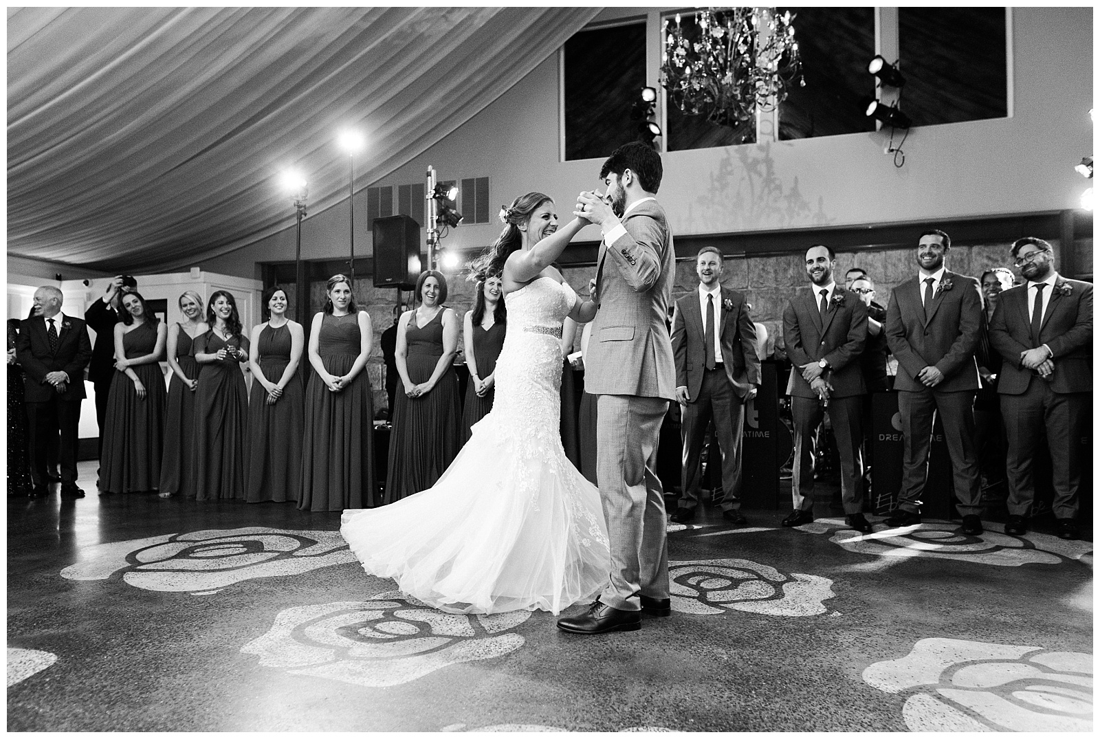 Black and white photo of the groom twirling the bride on the dance floor at the Lake House Inn wedding venue.