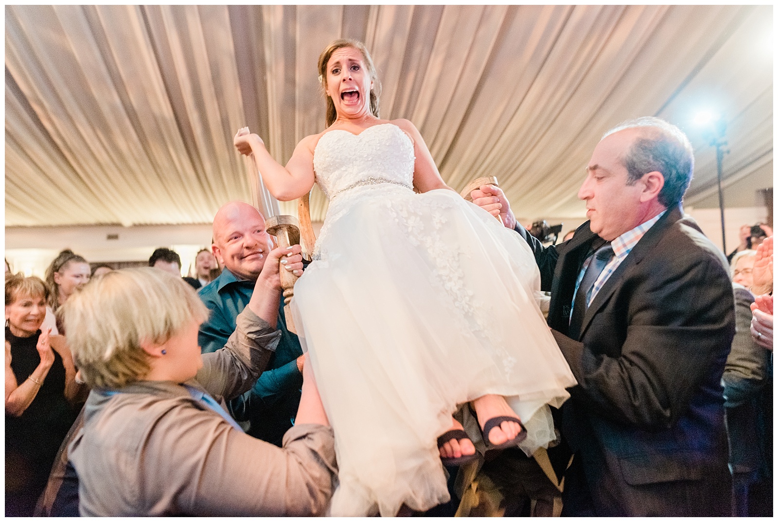 Bride screams while lifted on a chair for the hora dance.