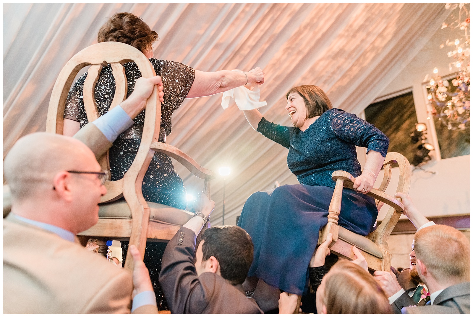 Both mothers are lifted up on chairs for the Jewish hora dance.