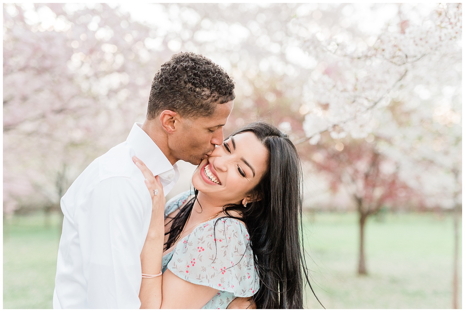 A man kisses his fiance on the cheek during a springtime engagement session.