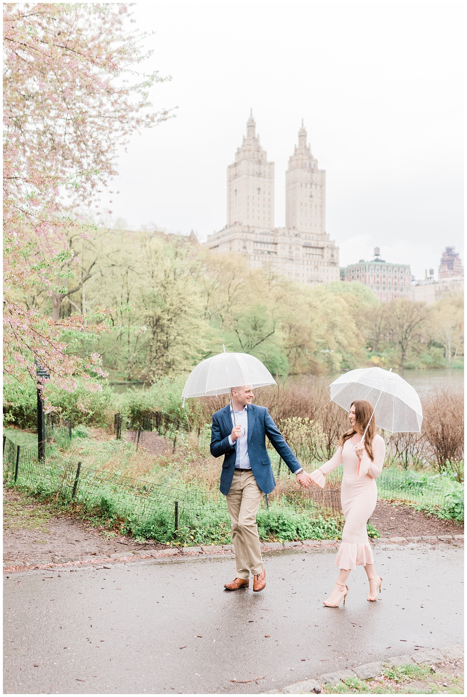 A couple holds hands walking through Central Park, NY in the rain.