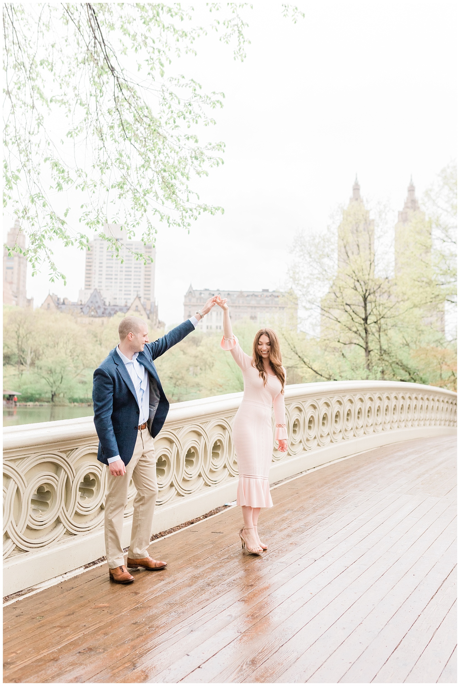 A man twirls his fiance while they slow dance on Bow Bridge in Central Park.