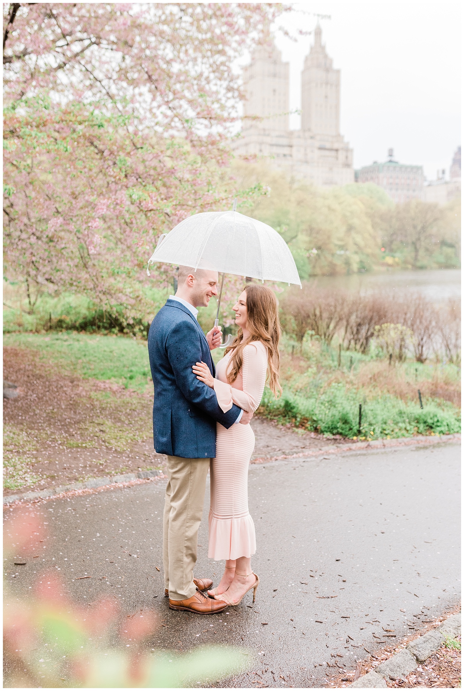 A couple smiles at each other under a clear umbrella as it rains in New York City.