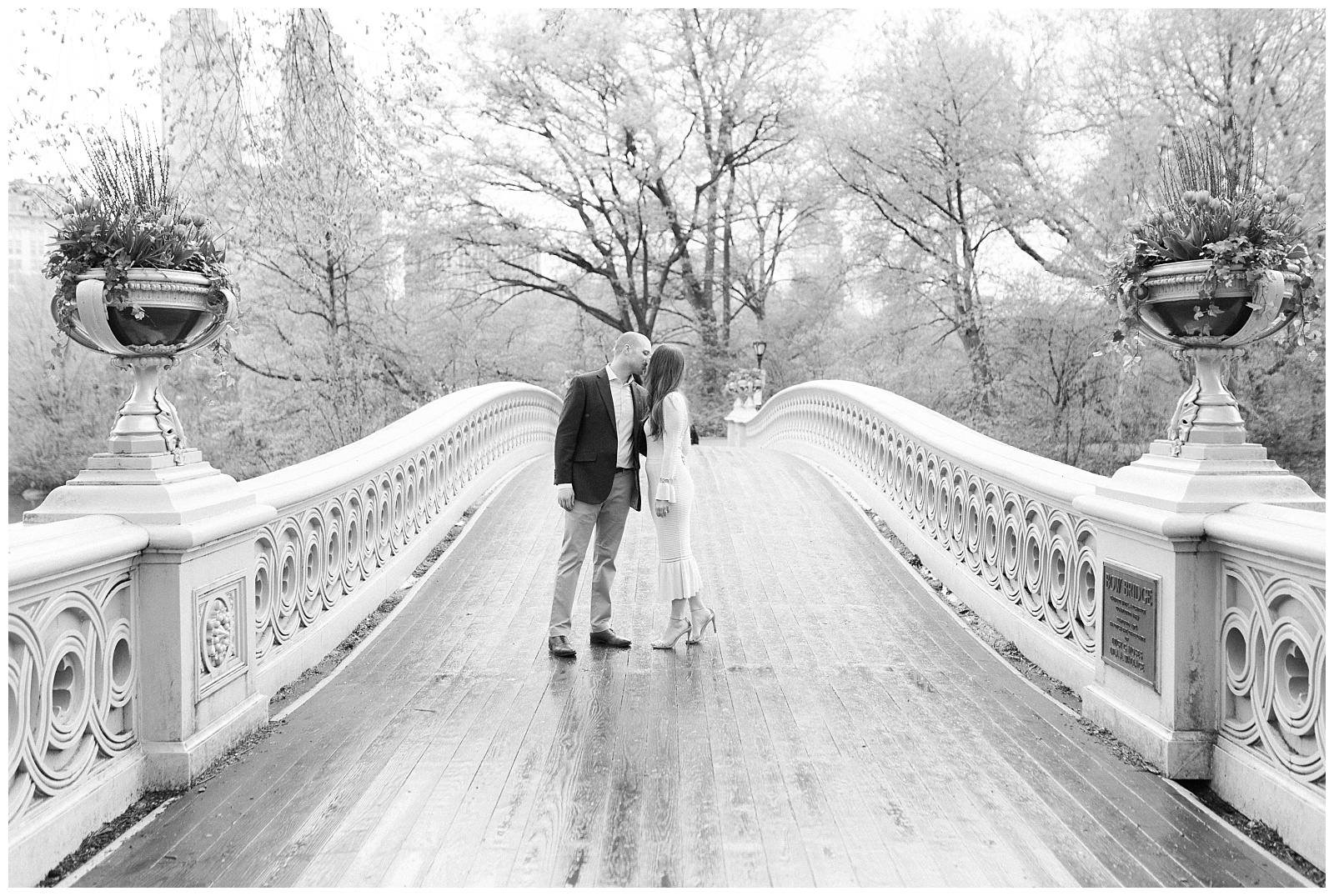 A couple kisses in the middle of Bow Bridge in the rain in Central Park.