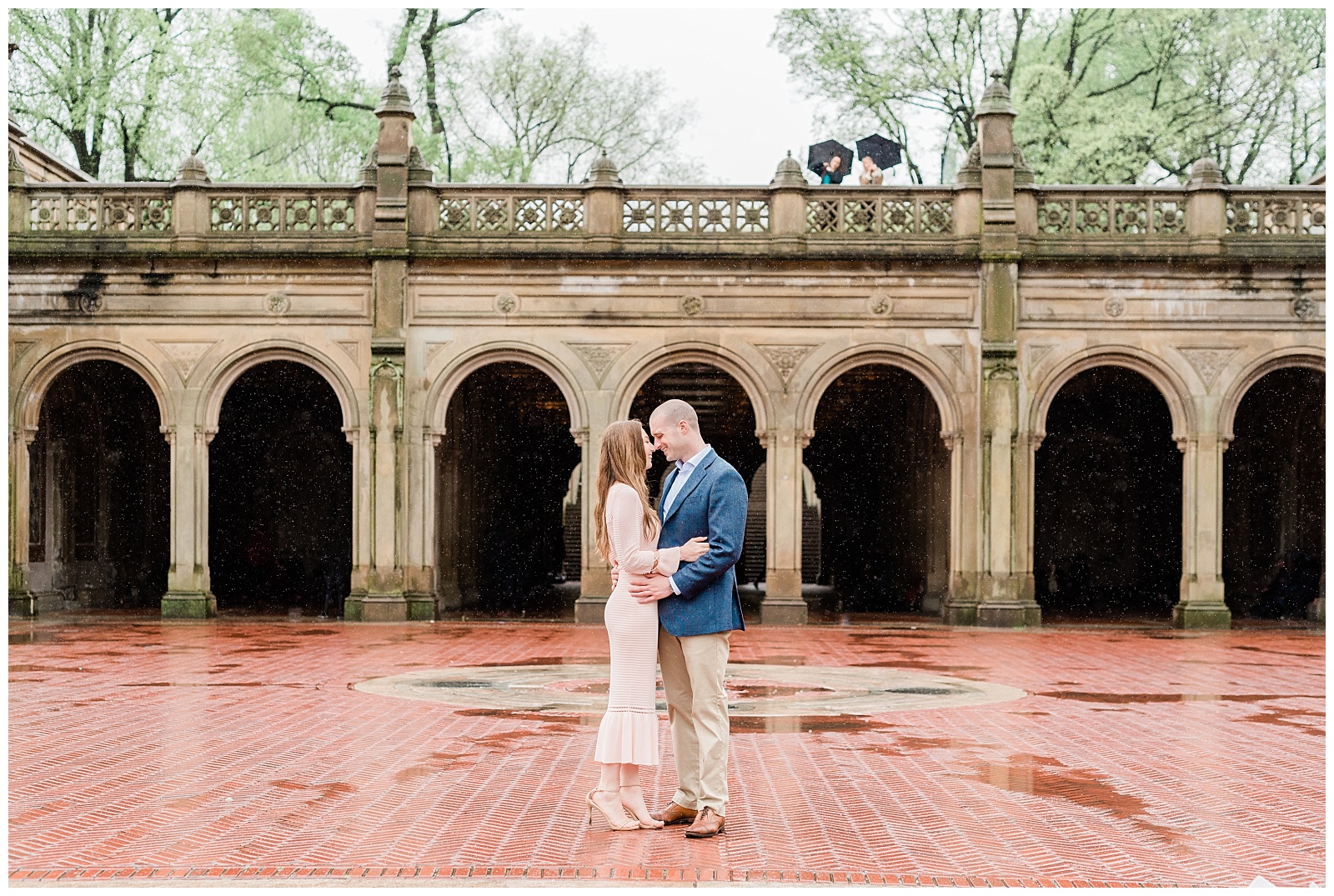 A couple holds each other in front of Bethesda Terrace arch ways in Central Park.