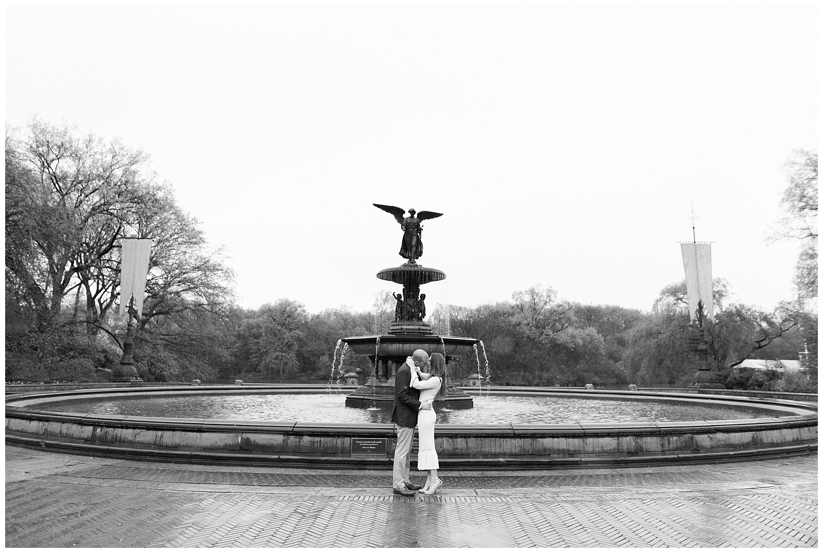 A couple kisses in the rain in front of Bethesda Fountain.