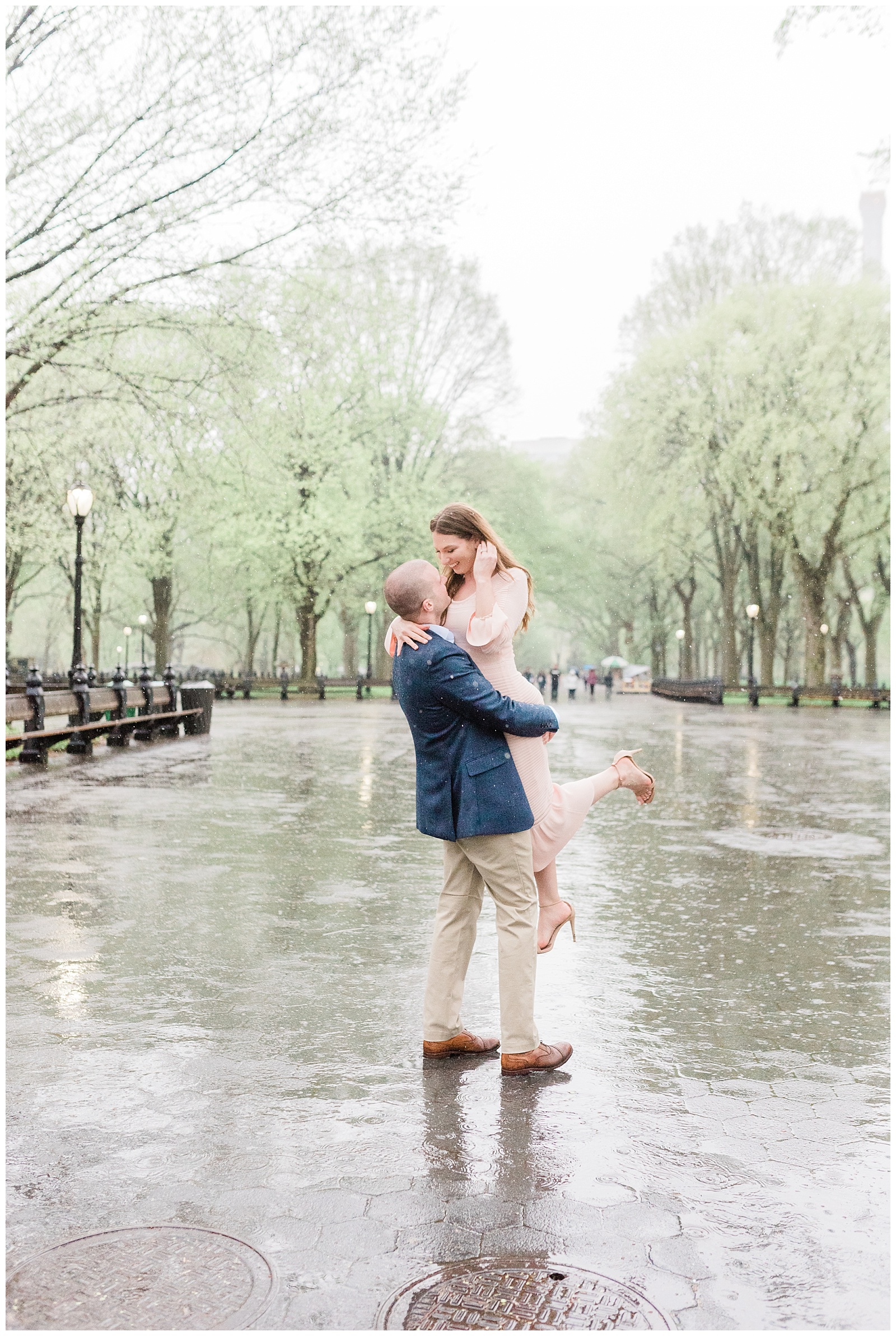 A man lifts his fiance in the rain in the Central Park Mall.