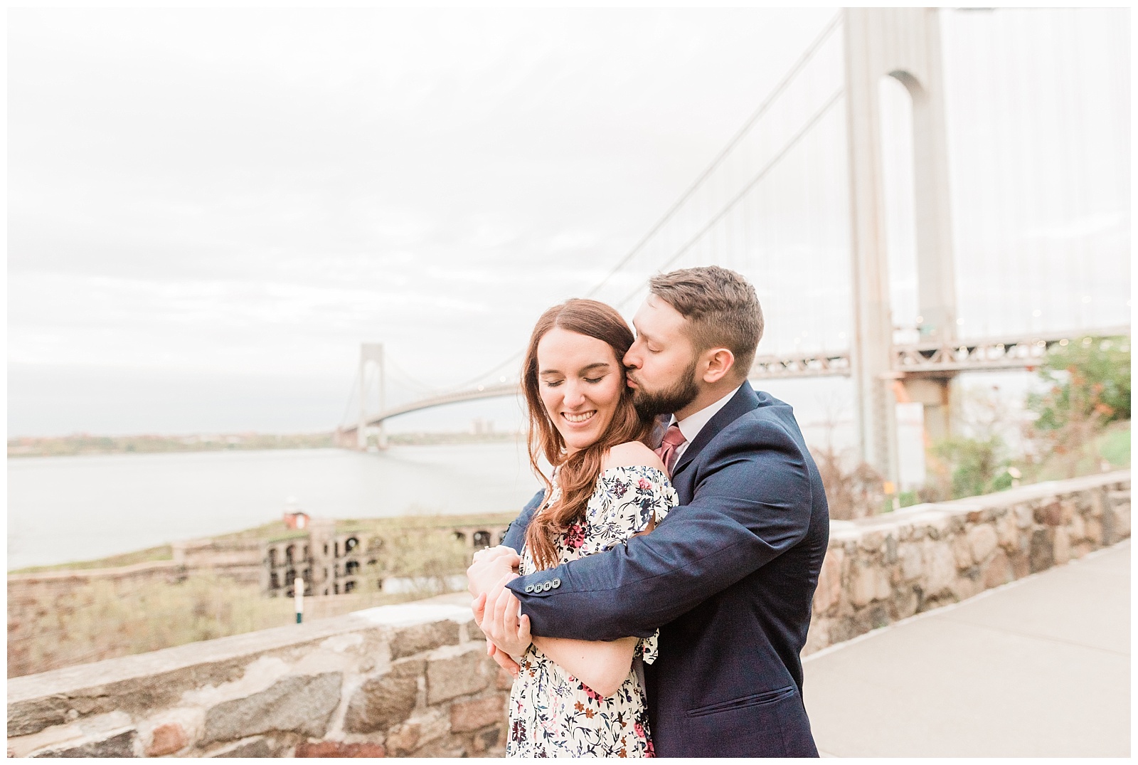 A man kisses his fiancee on the temple by the Verrazzano Bridge in Staten Island.