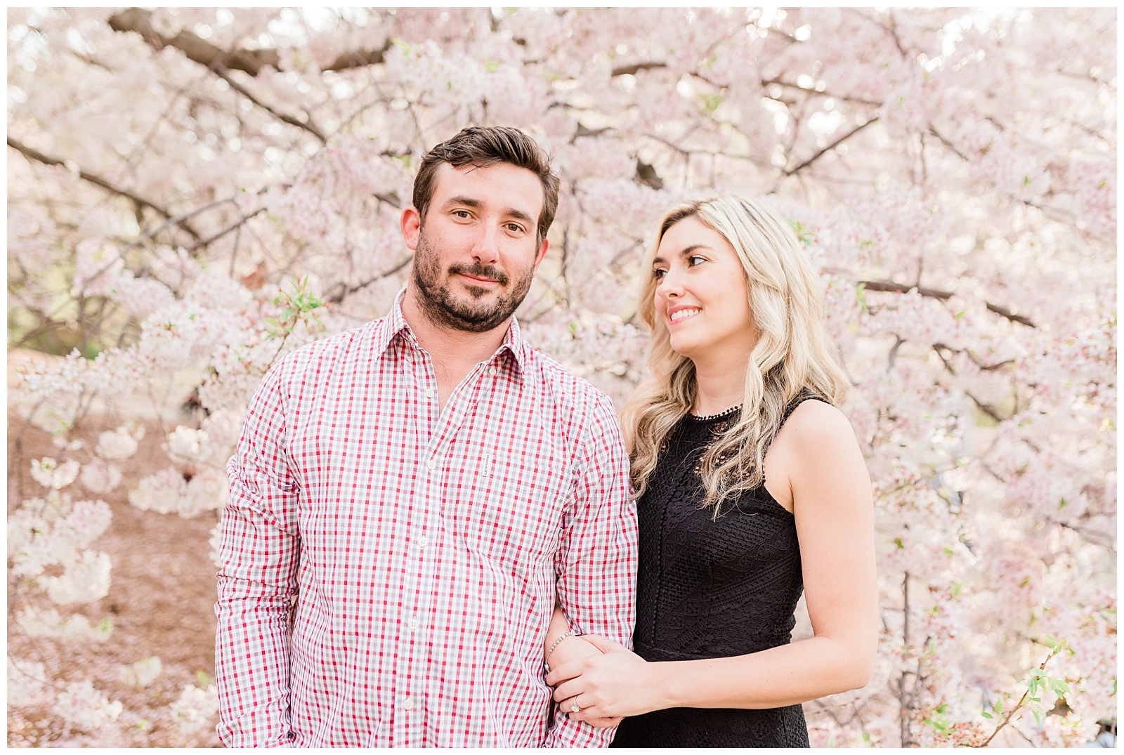 A woman looks at her fiance in front of a blooming cherry blossom tree in New York.