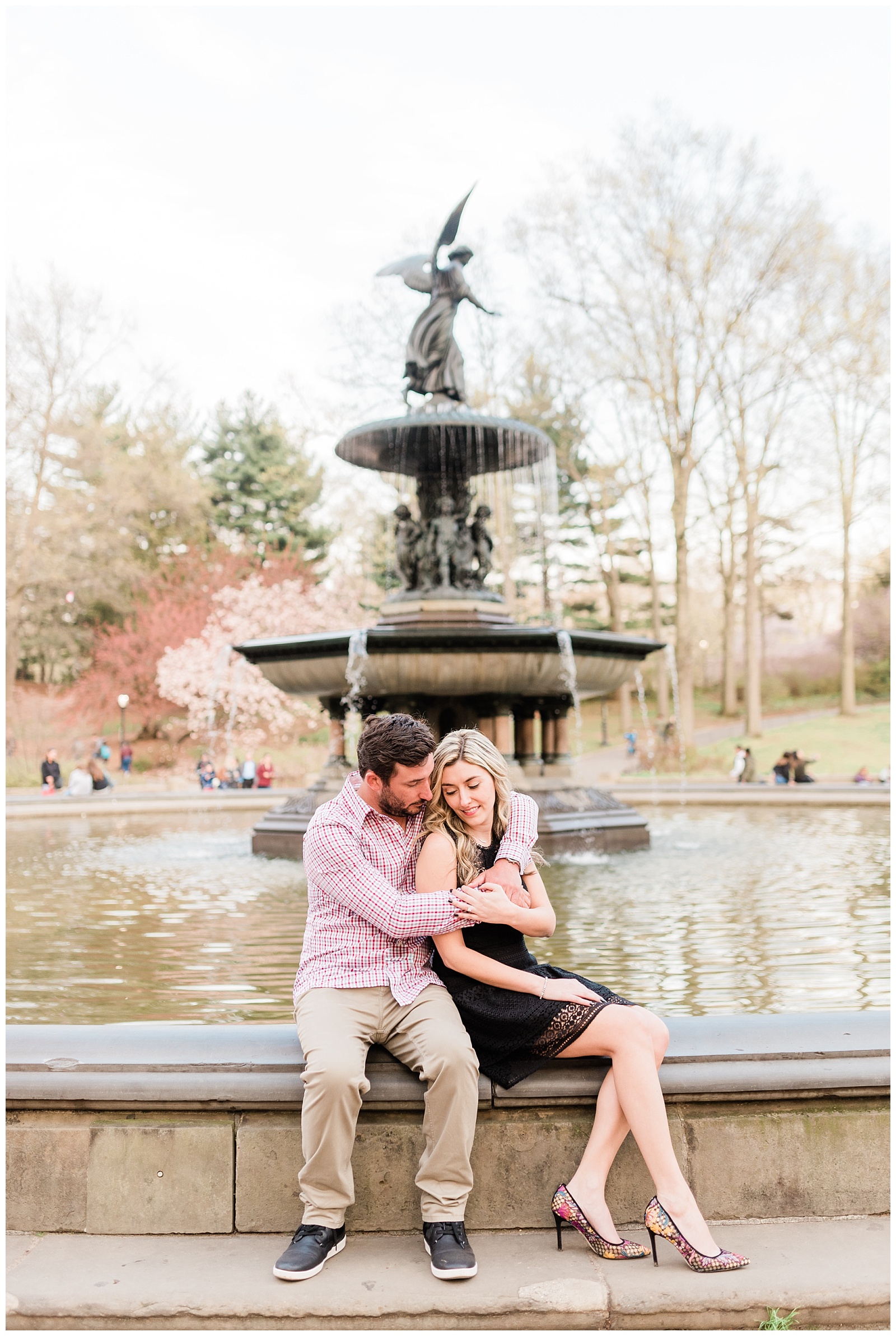 A couple sits together on the edge of Bethesda Fountain.