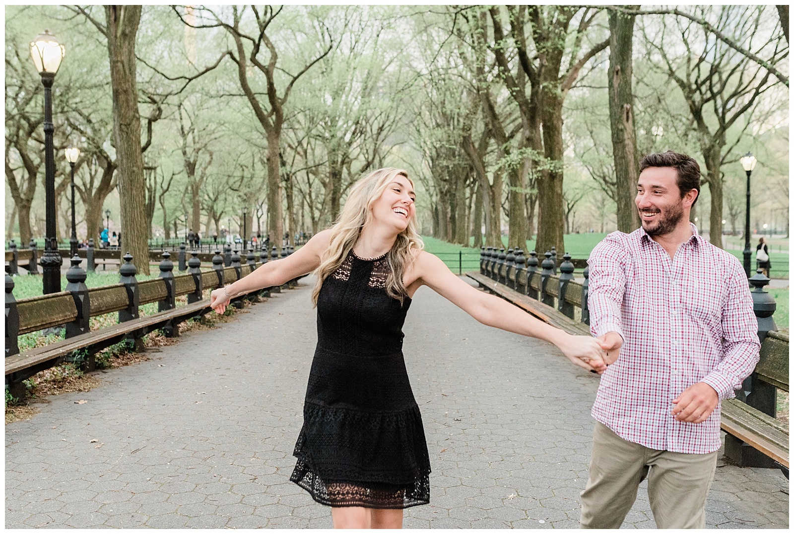 A man and woman laugh together holding hands in the Mall at Central Park, NYC.