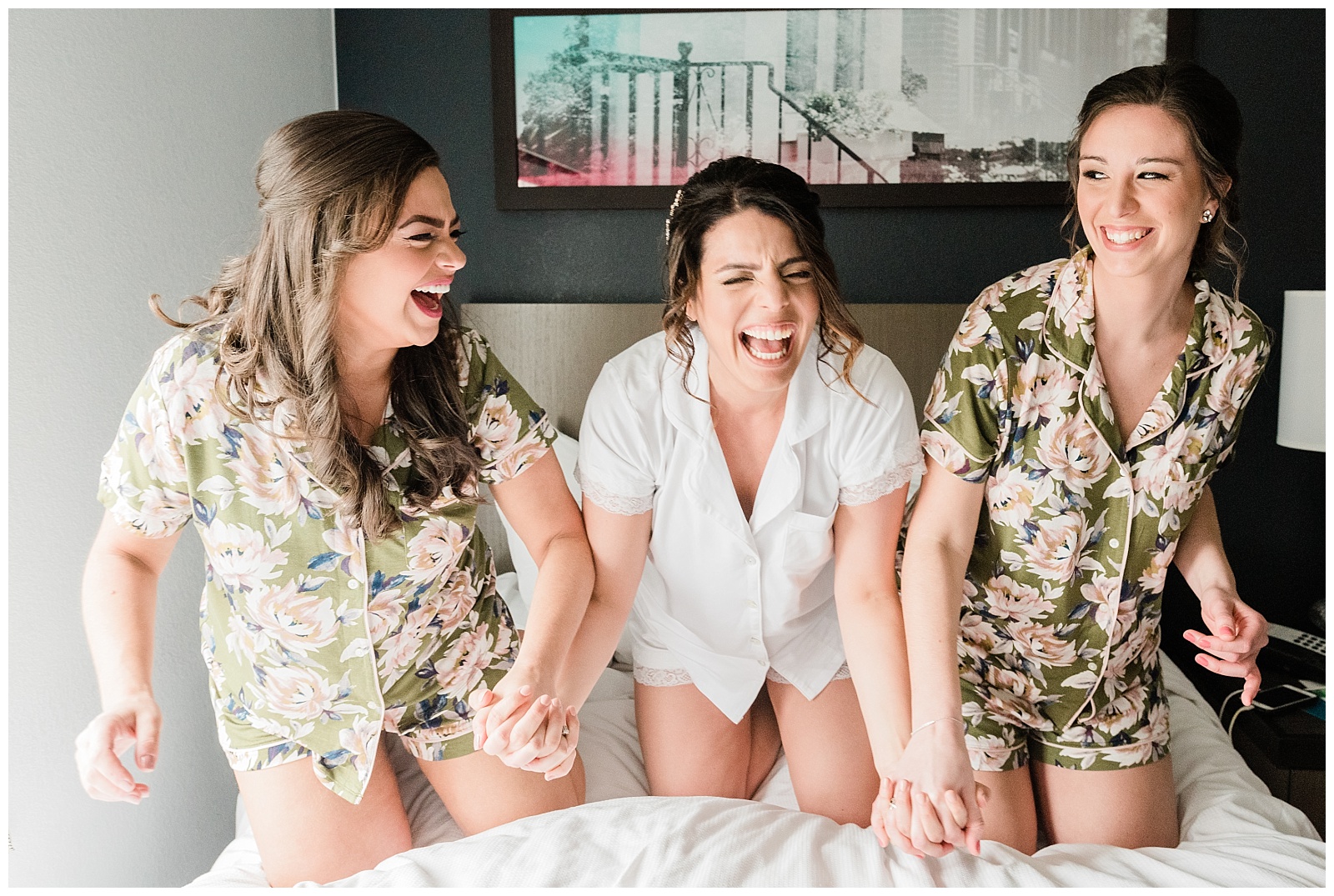 Bride and bridesmaids laughing, holding hands while wearing matching pajamas.