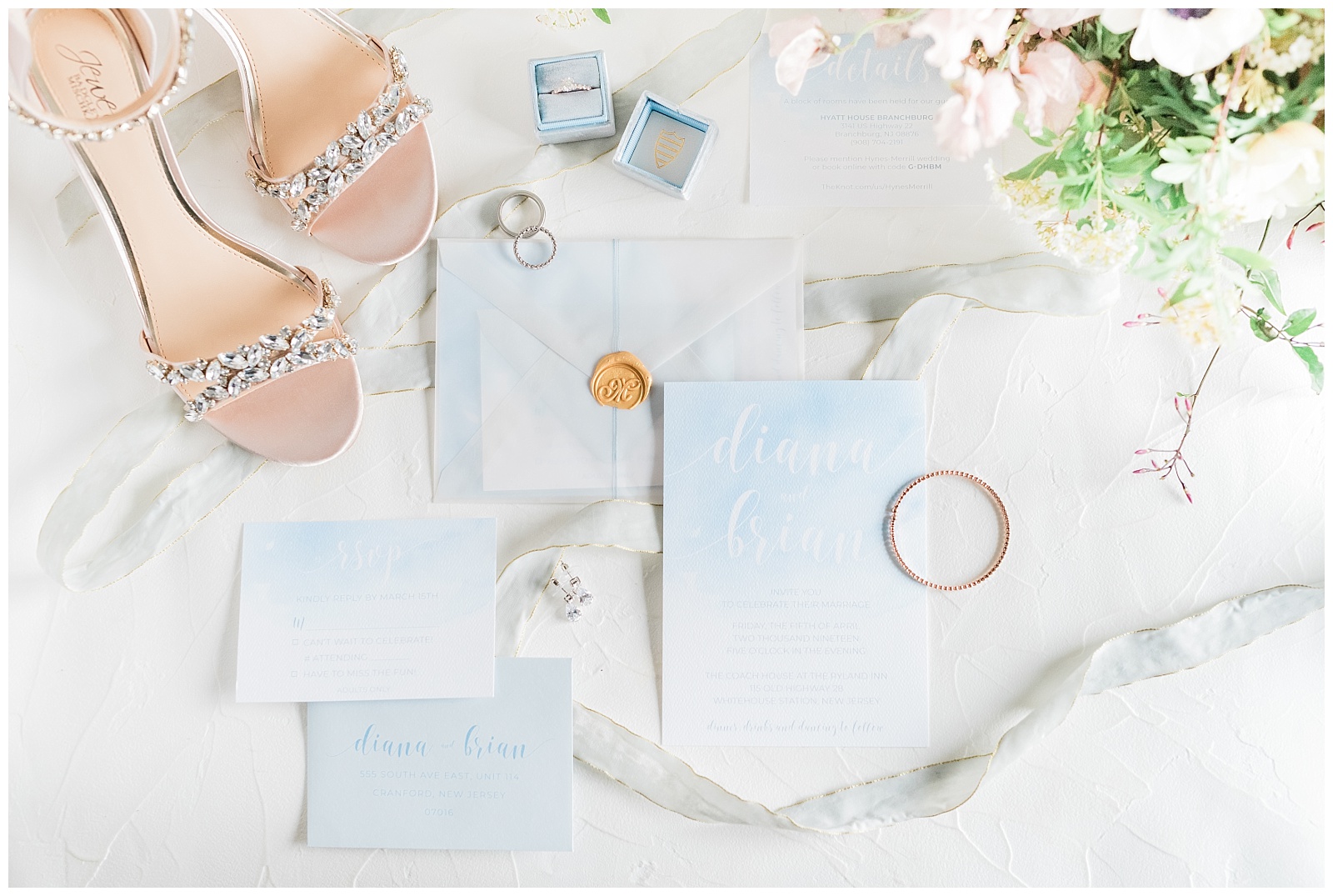 A blue watercolor invitation suite styled with Badgley Mischka shoes and wedding rings.