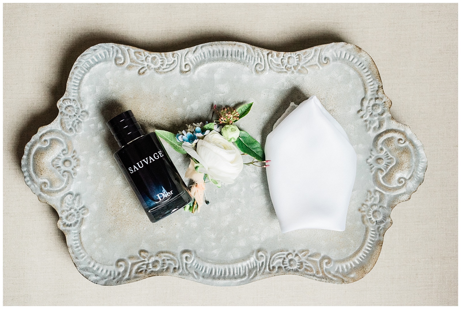 Groom's cologne, boutonniere and pocket square styled on a tray.