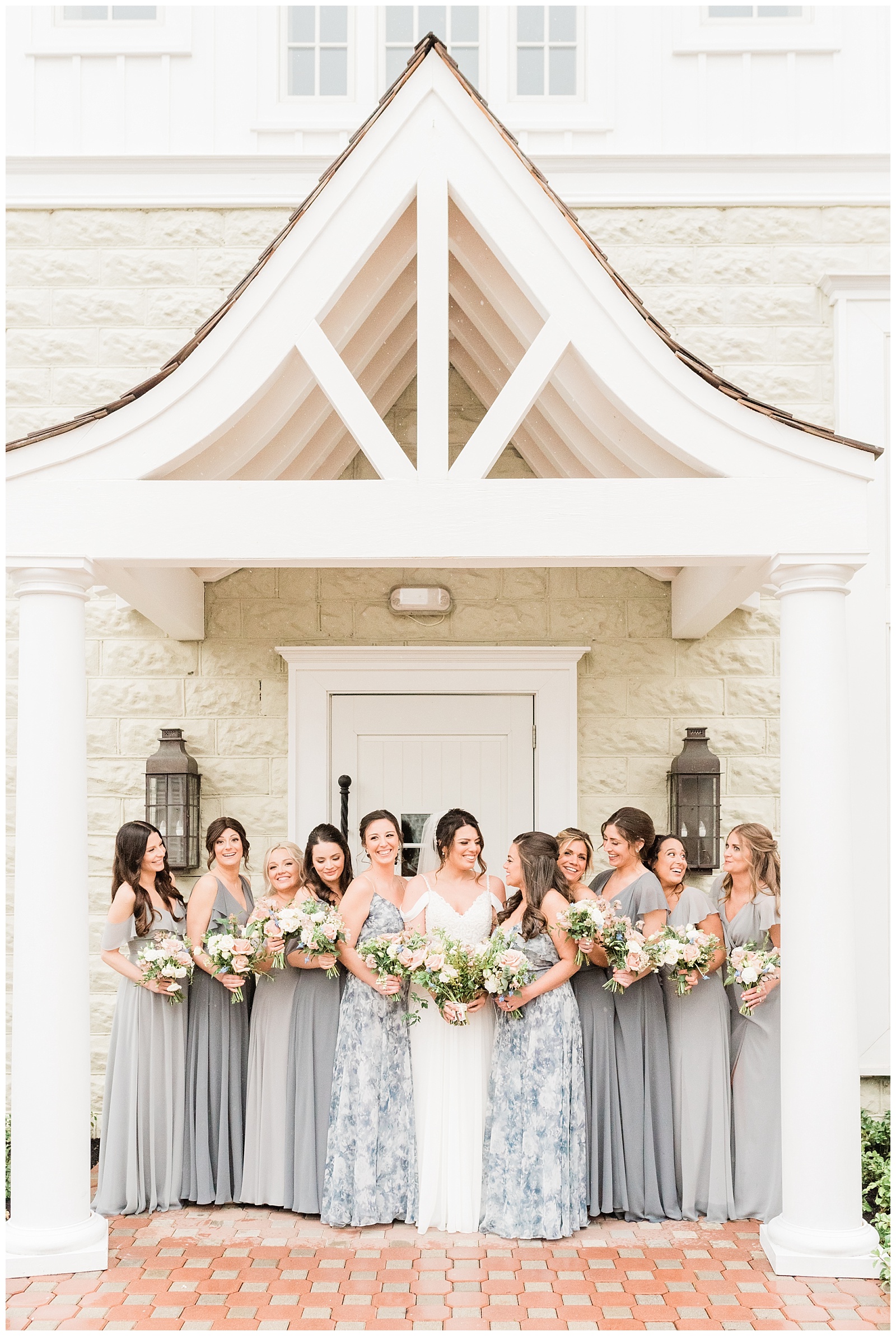 The bride laughs with her bridesmaids under an awning at the Coach House at the Ryland Inn.