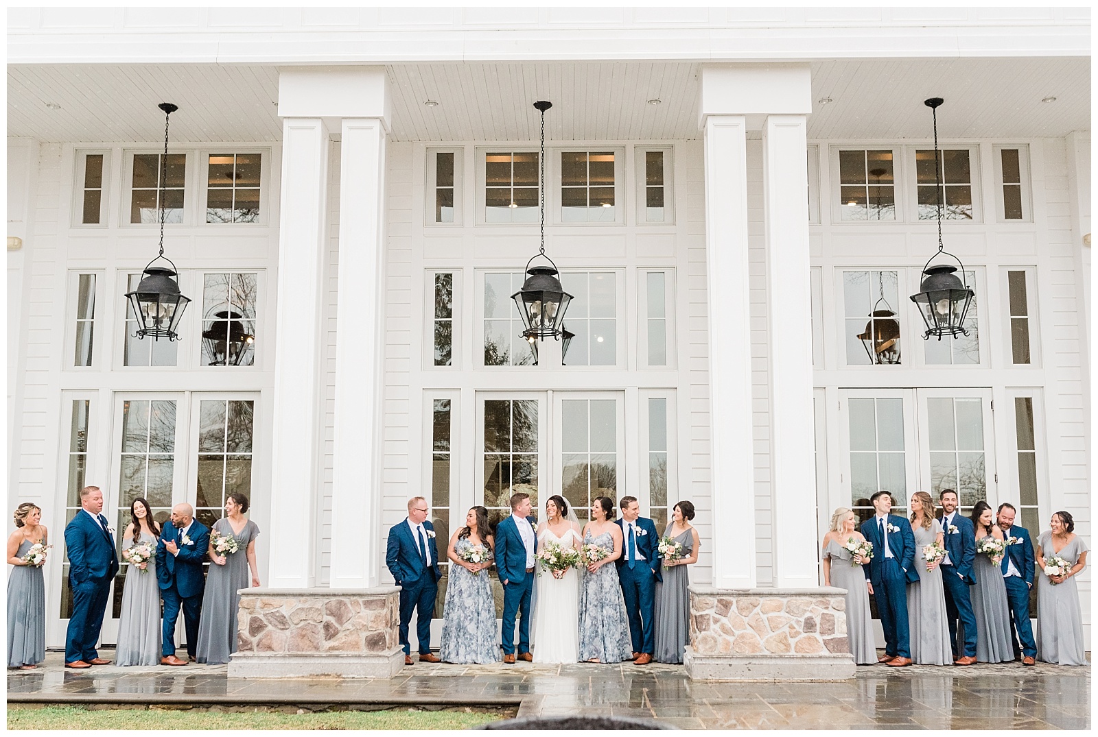 Bridesmaids and groomsmen look at each other and laugh outside the Ryland Inn.
