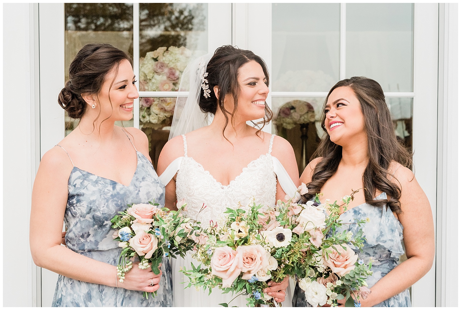 Bride and her maids of honor look at each other and smile.