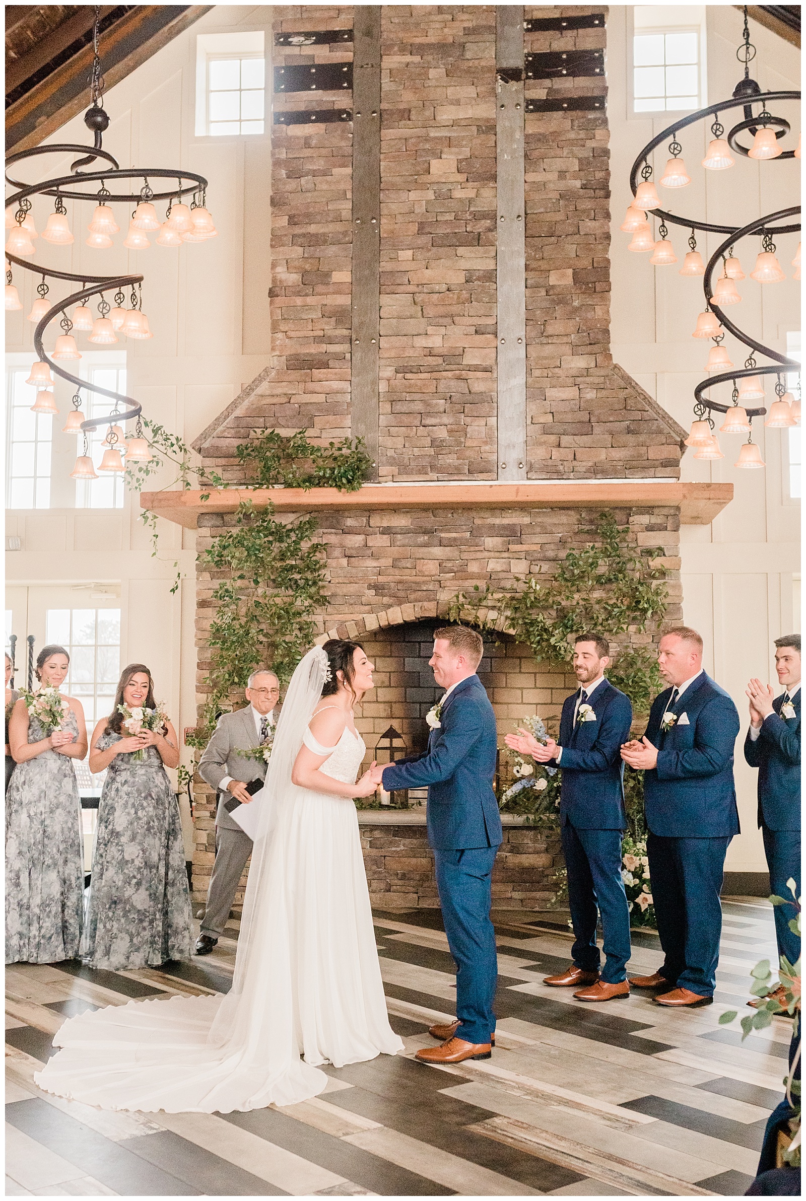 Bride and groom exchange vows in front of a stone fireplace during their wedding ceremony.