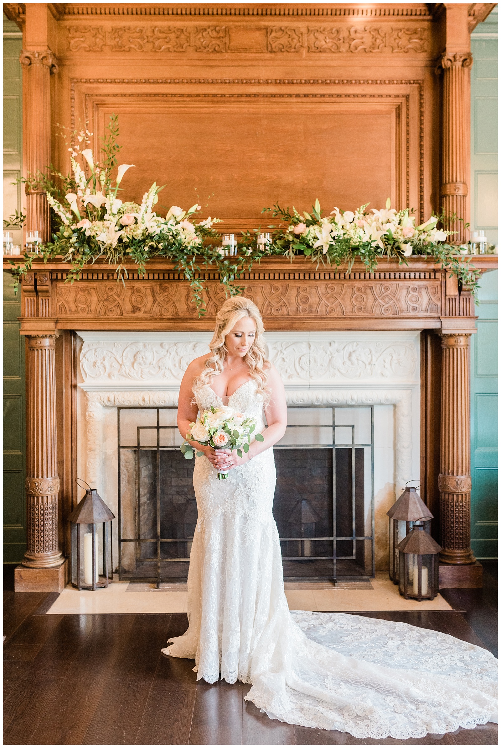 A bride holds her bouquet in front of a floral covered fireplace in the Mansion at Natirar.