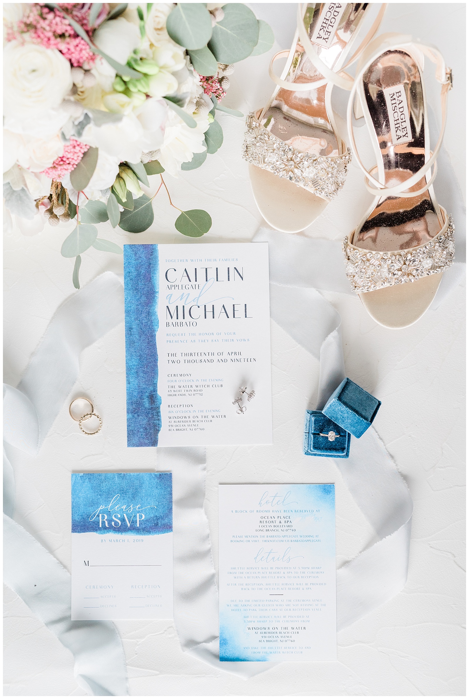 A blue wedding invitation suite is styled with Badgley Mischka Shoes and a blue velvet ring box.