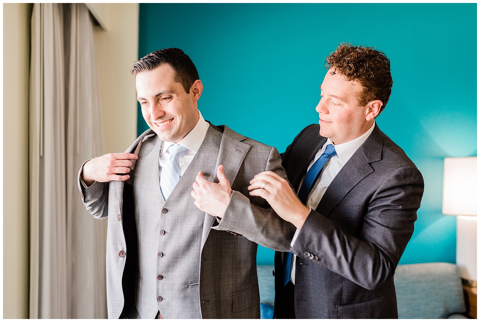 Best man helps groom put on his jacket.