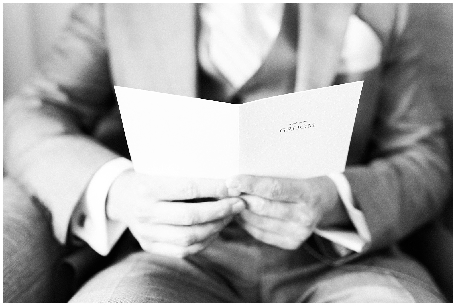 Close up of groom reading a card from the bride in black and white.