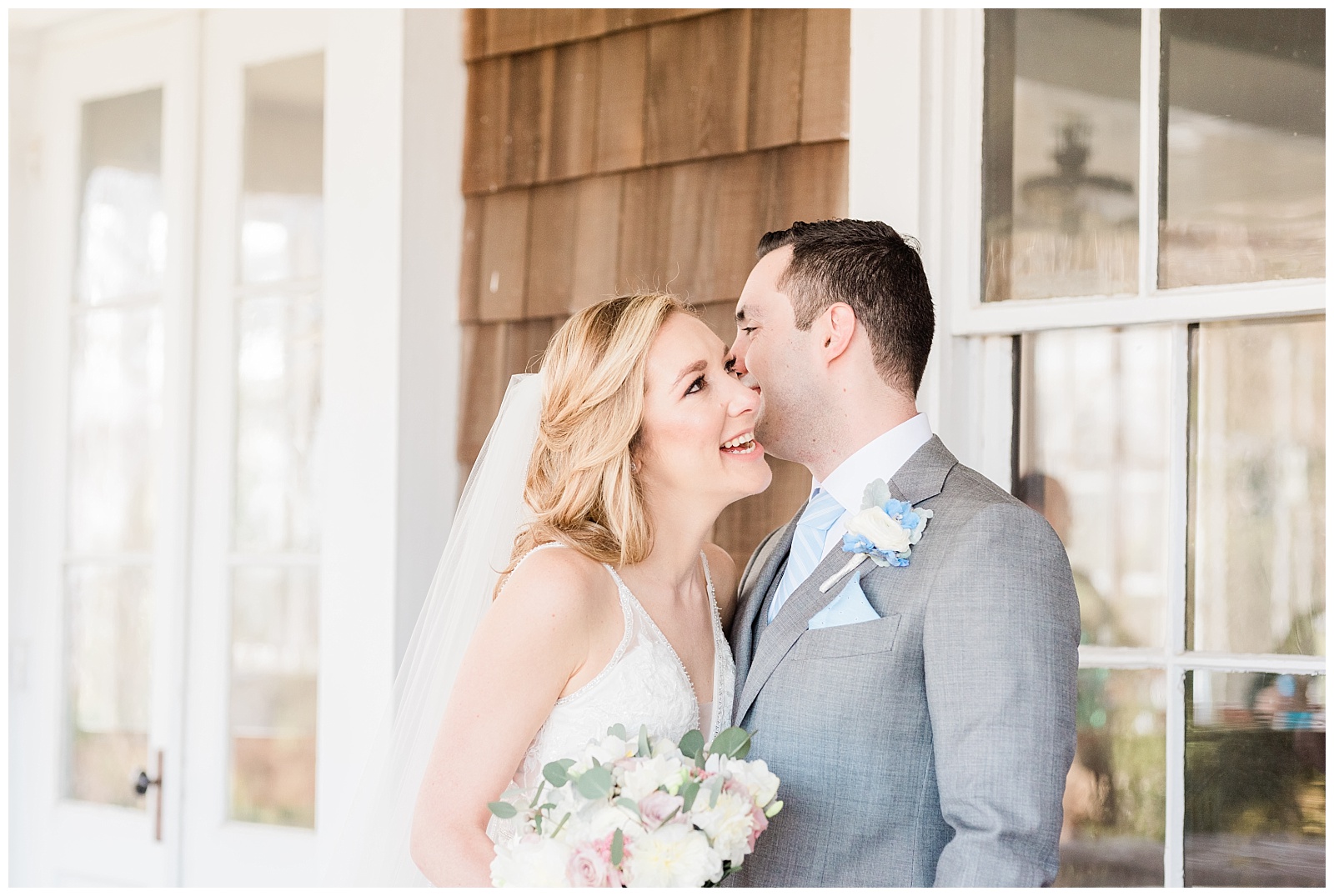 Bride laughs while groom whispers in her ear.