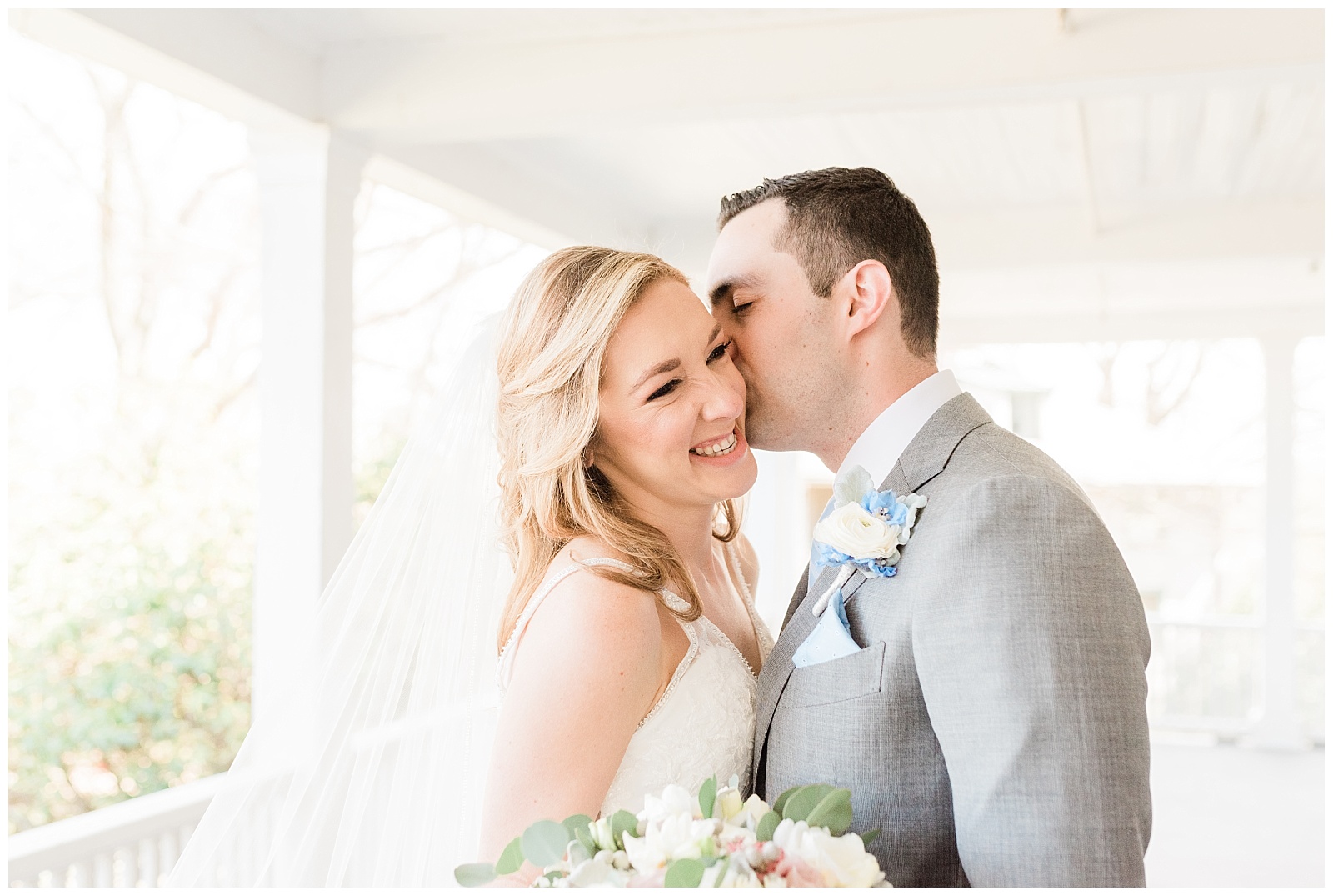 Groom kisses a bride's cheek while she laughs.