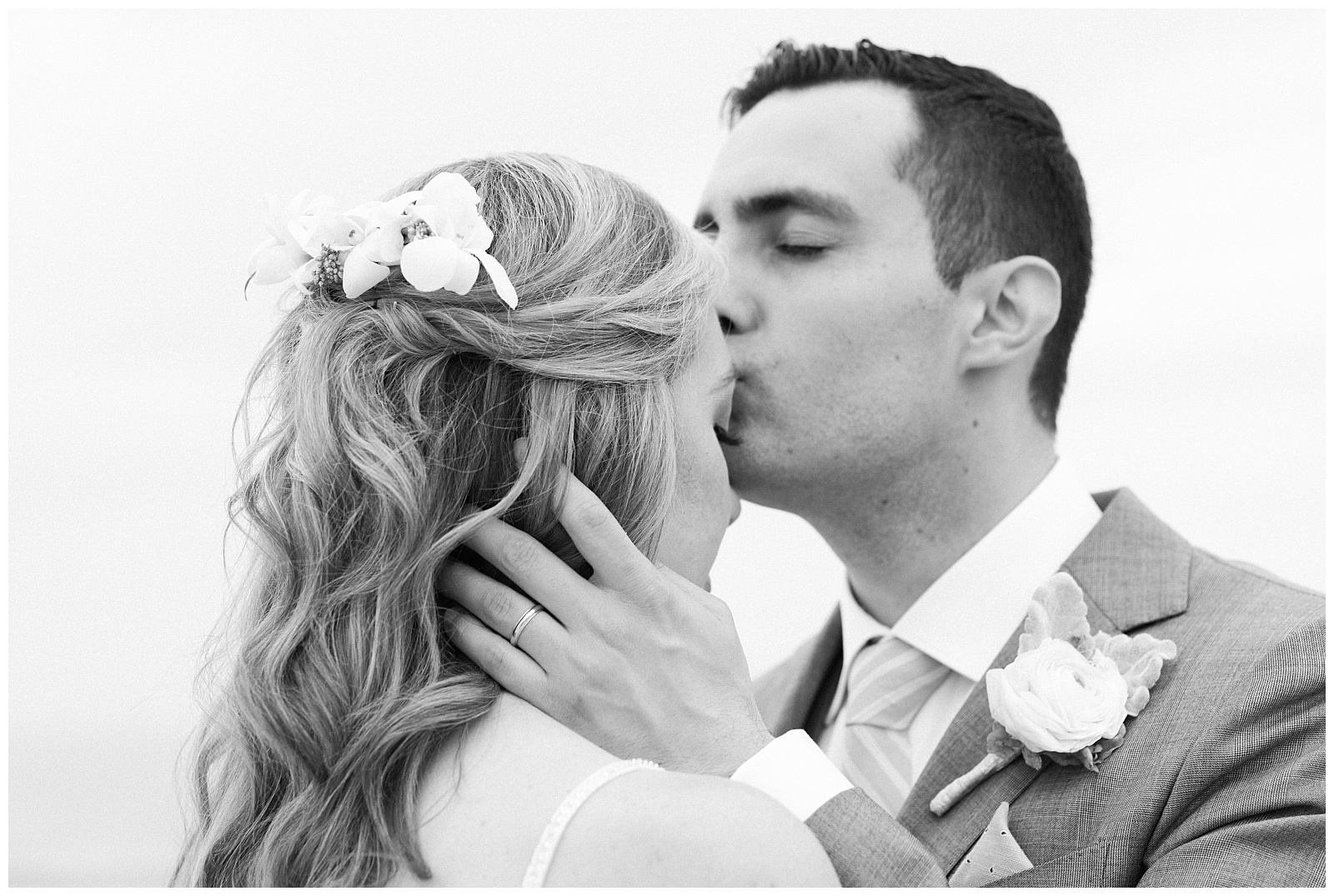 Groom kisses the bride's forehead and holds her hair.