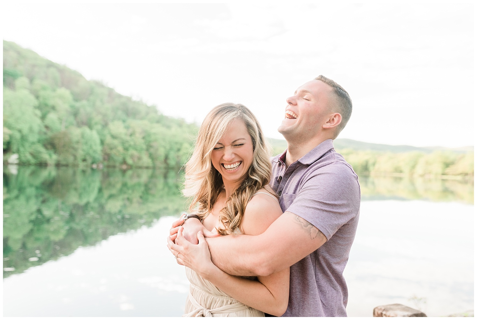 A man holds his fiancee from behind laughing together.