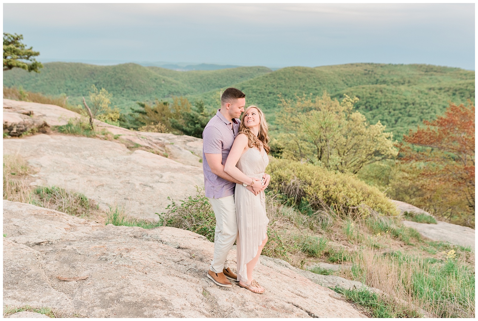 A couple holds each other at golden hour on top of Bear Mountain.