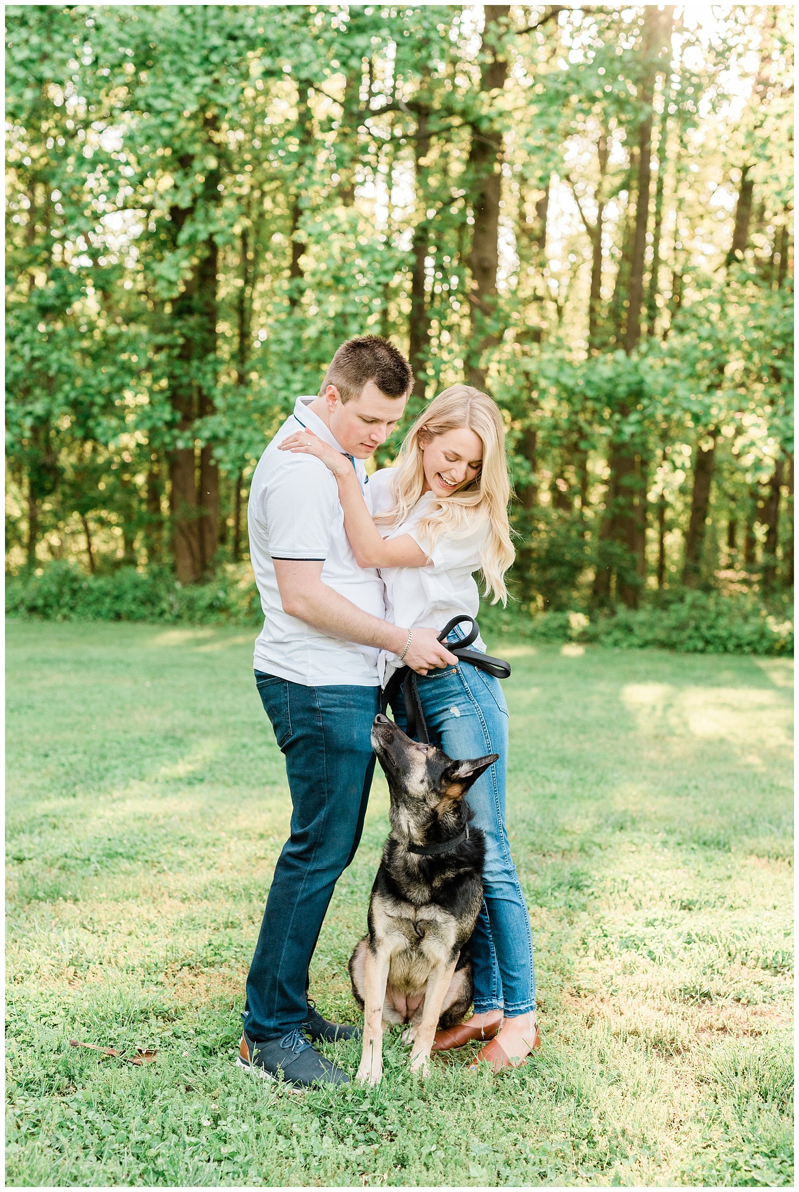 A couple holds on to each other, looking down at their German Shepherd dog.