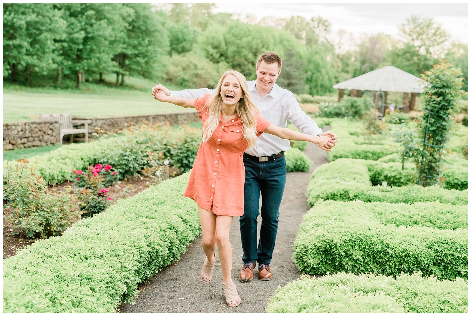 A couple holds hands laughing together through the gardens.