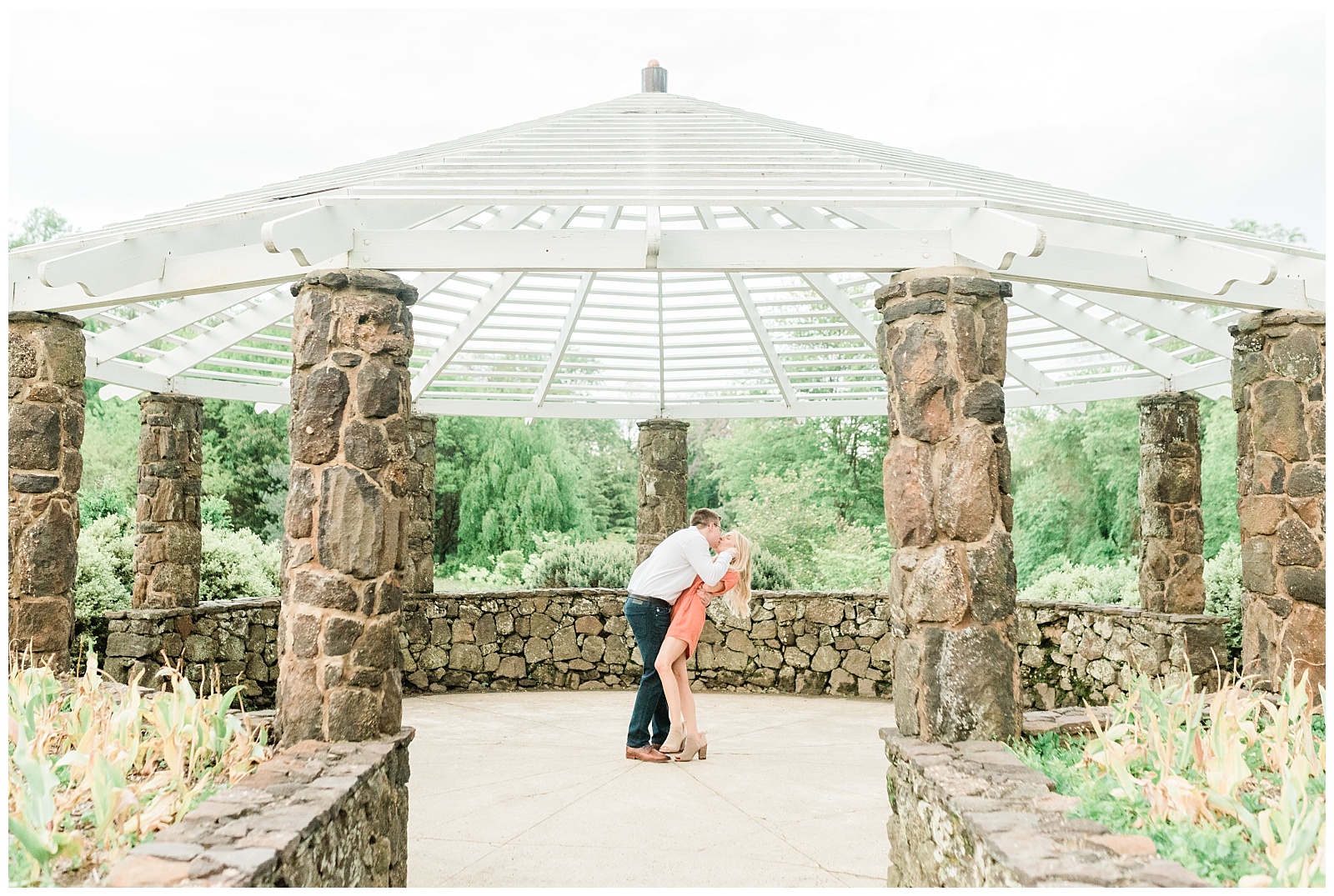 A man dips back his fiancee for a kiss under the gazebo in Deep Cut Gardens.
