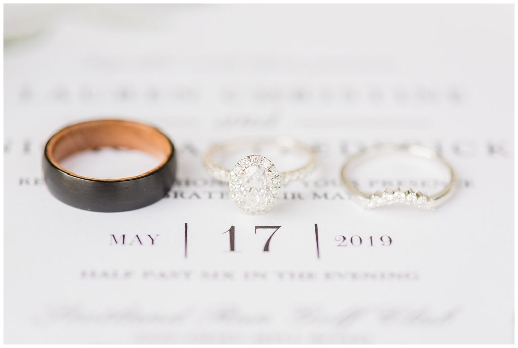 Wedding rings sit on top of a wedding invitation.