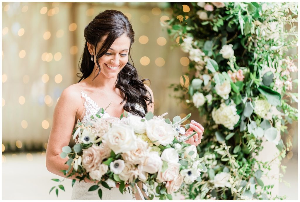 A bride looks at her bouquet and smiles.