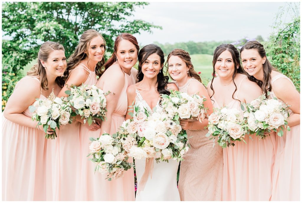 A bride and her bridesmaids smile posing for a photo.