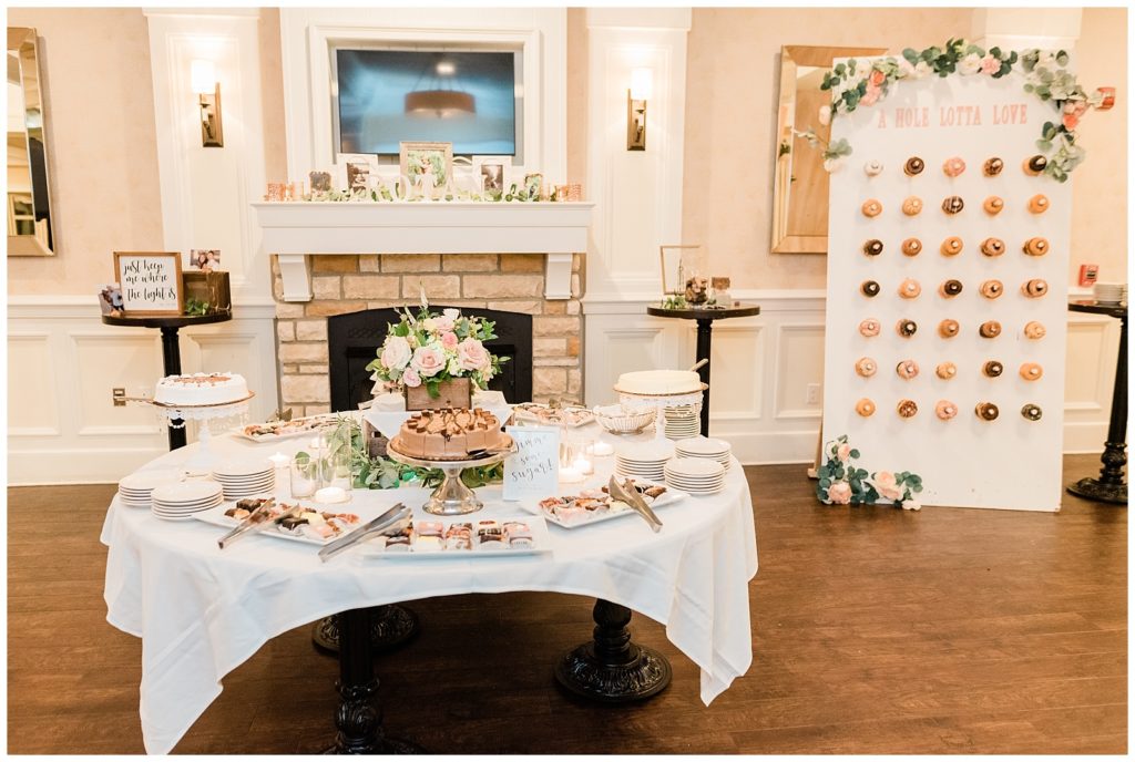 A dessert display sits near a donut wall during the wedding reception.