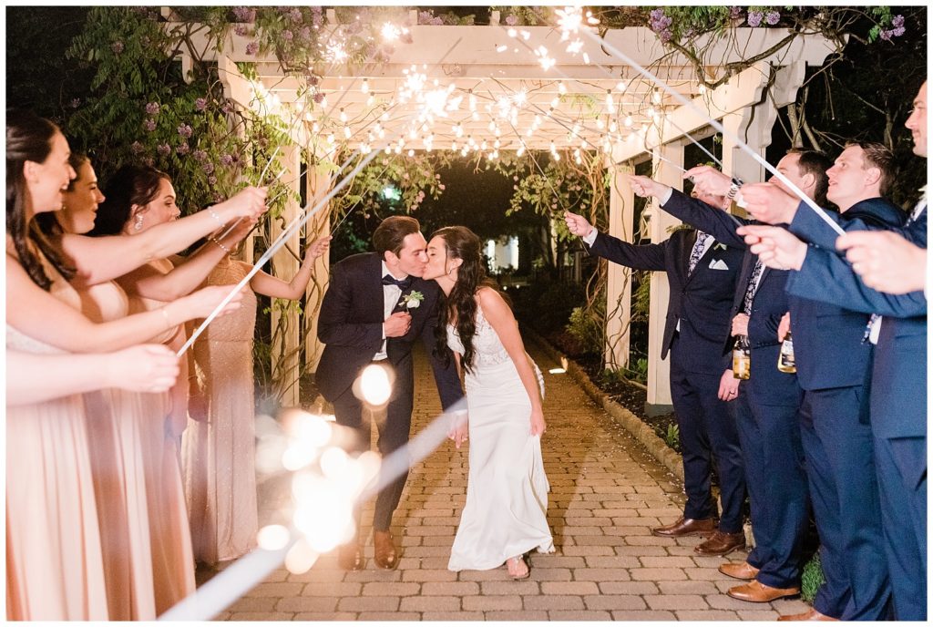 A bride and groom kiss during a sparkler send off at the end of the reception.