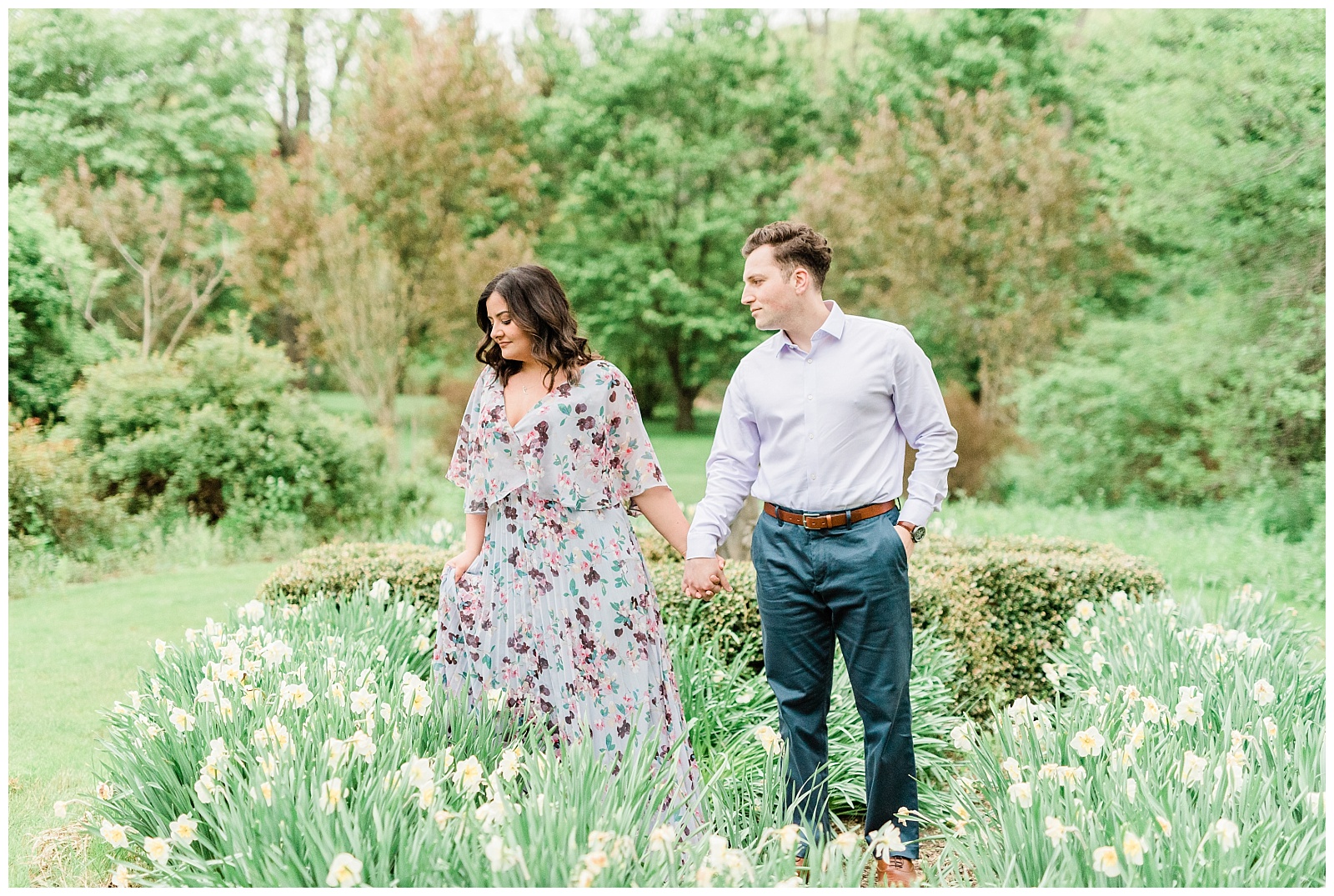 A woman leads a man through a field of blooming flowers.
