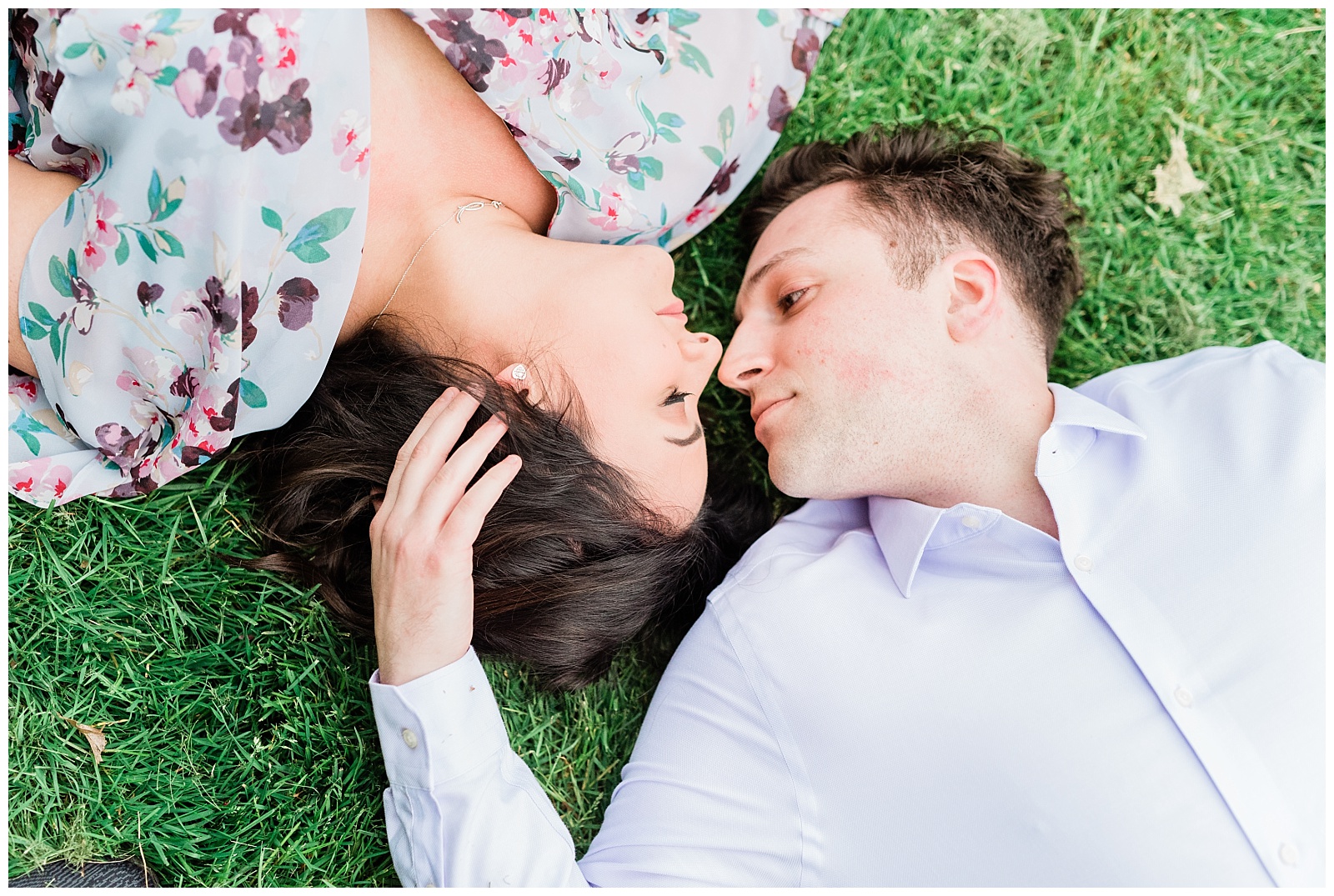 A couple lays together on the ground with their noses together.