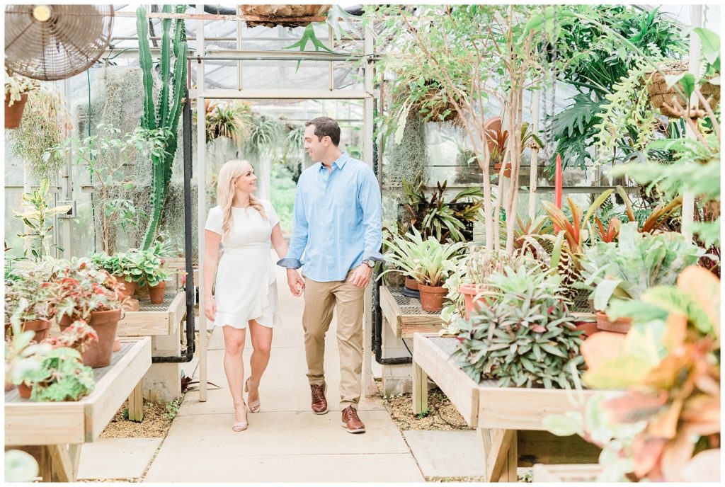 A man and woman hold hands walking through the greenhouse at Deep Cut Gardens.