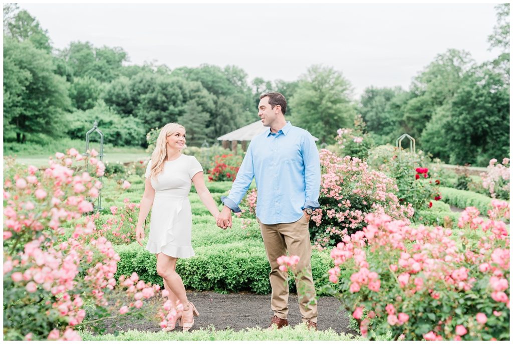 A couple holds hands in a blooming garden.